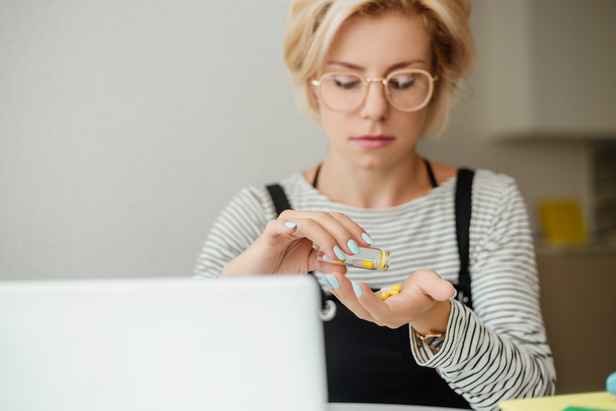 Young woman pouring out pills on hand